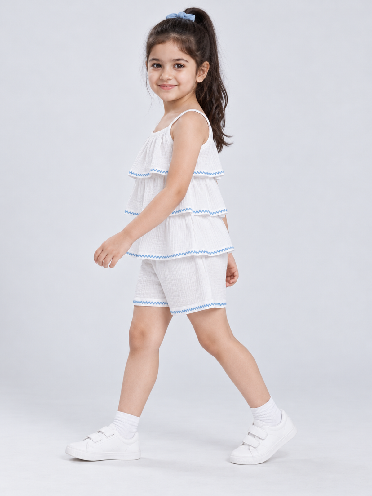 Side view of girls white and blue embroidered cotton muslin top and shorts set